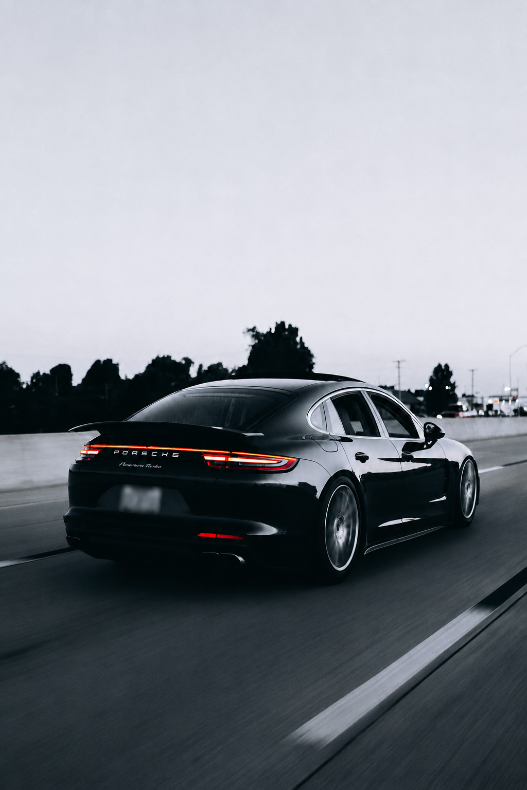 Elegant svart Porsche Panamera i fart på veien i skumring
